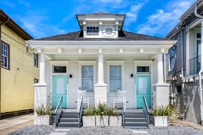A two-story house with a front porch, a small attic window, and a green door. - Luxury 4BR in Uptown NOLA (New Orleans)