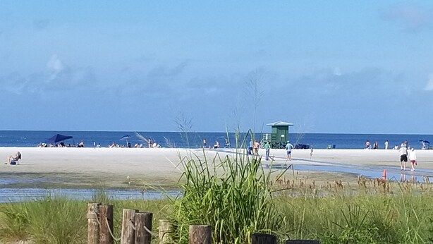 Ein Strand mit einem Rettungsturm, sandigem Ufer und Rasenflächen.