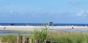 Ein Strand mit einem Rettungsturm, sandigem Ufer und Rasenflächen.