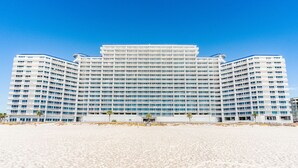 A large, multi-story hotel with a symmetrical facade, located on a sandy beach. - Lighthouse Condominiums (Gulf Shores)