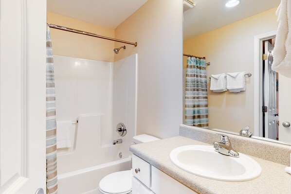 A bathroom with a bathtub, toilet, and sink. - Lighthouse Condominiums (Gulf Shores)