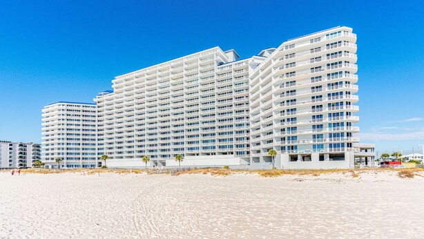 A large, multi-story hotel with a modern design, located near a sandy beach. - Lighthouse Condominiums (Gulf Shores)