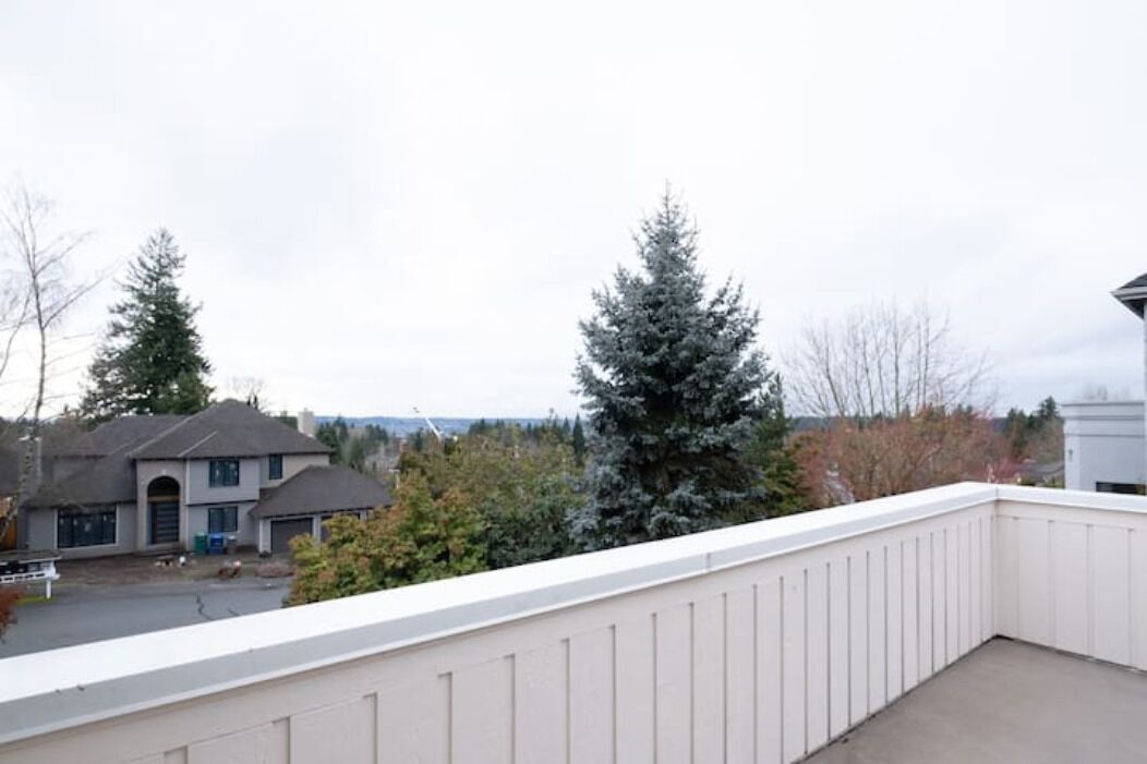A residential balcony with a view of a house and trees.