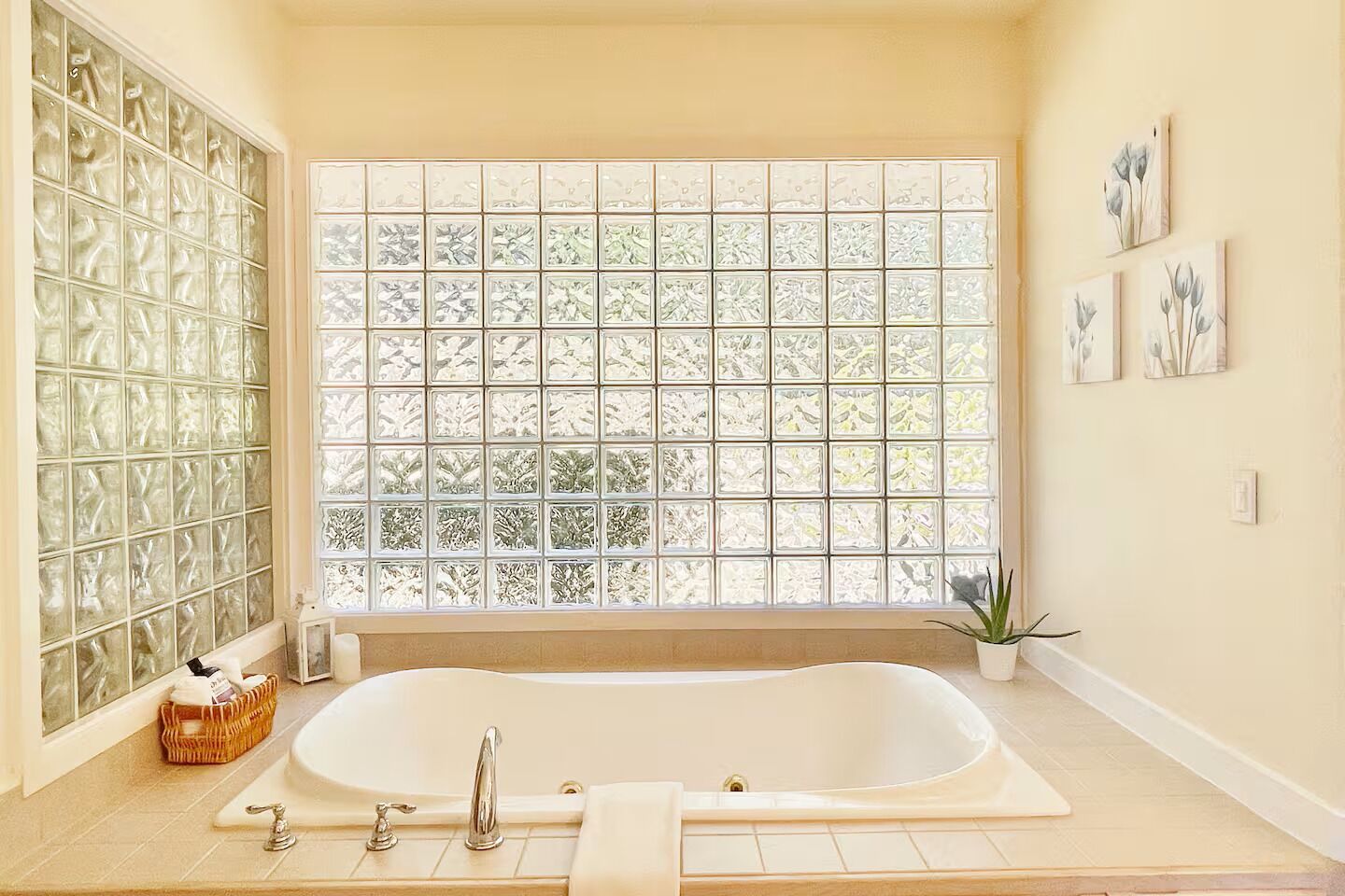 A bathroom with a large window, a bathtub, and a wicker basket.