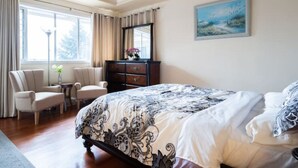 Una camera da letto con un letto grande, una cassettiera, due sedie e una finestra con tende.