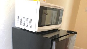 Una cucina compatta con un frigorifero nero e un forno a microonde sopra.