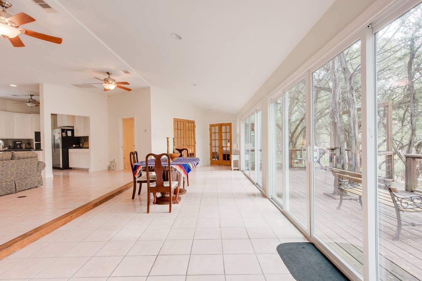 A spacious living area with a dining table, chairs, and a view of the outdoors through large windows.