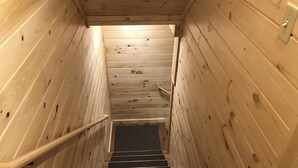 Eine Holzt Treppe mit Handlauf, die zu einer Zwischenebene mit einem Lichtschalter führt.