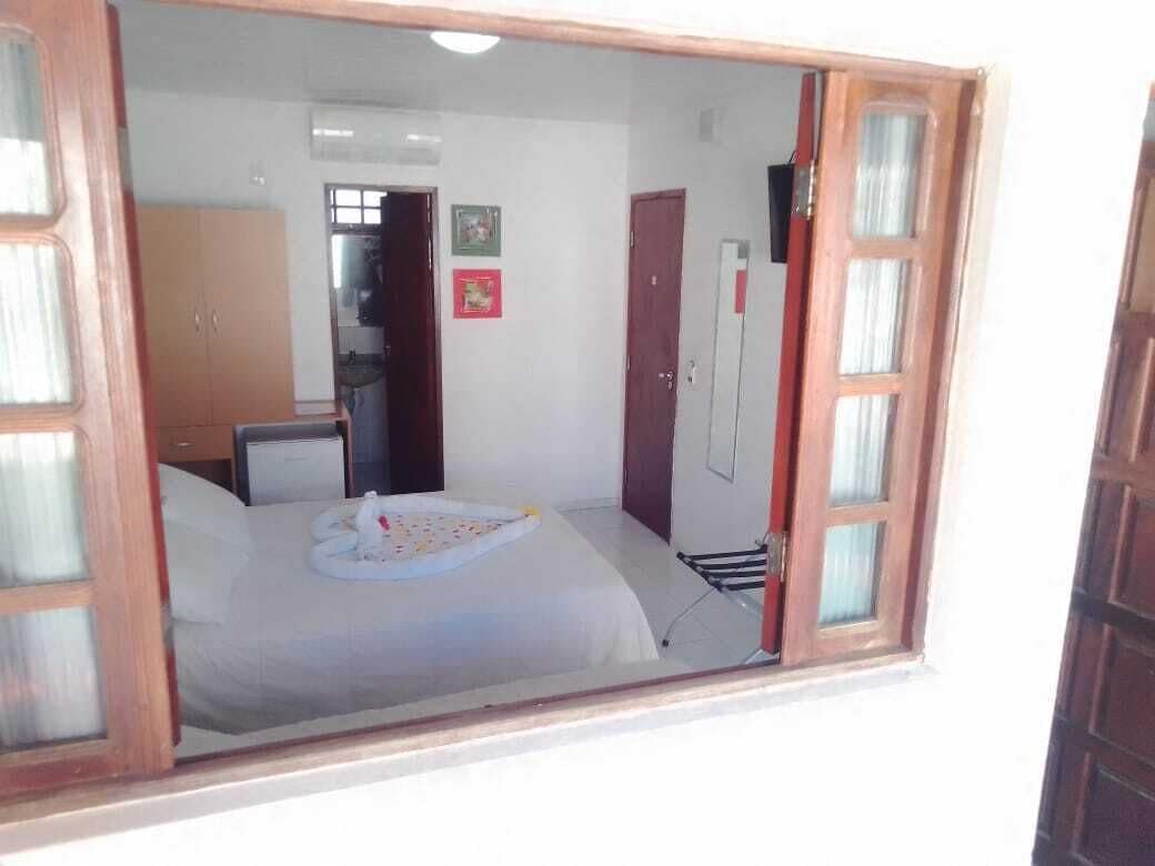 A bedroom with a bed, a small desk, and a wardrobe.