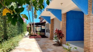 A modern building with blue and white exterior walls, a paved pathway, and various plants. - Pousada Lua Azul (Ipojuca)