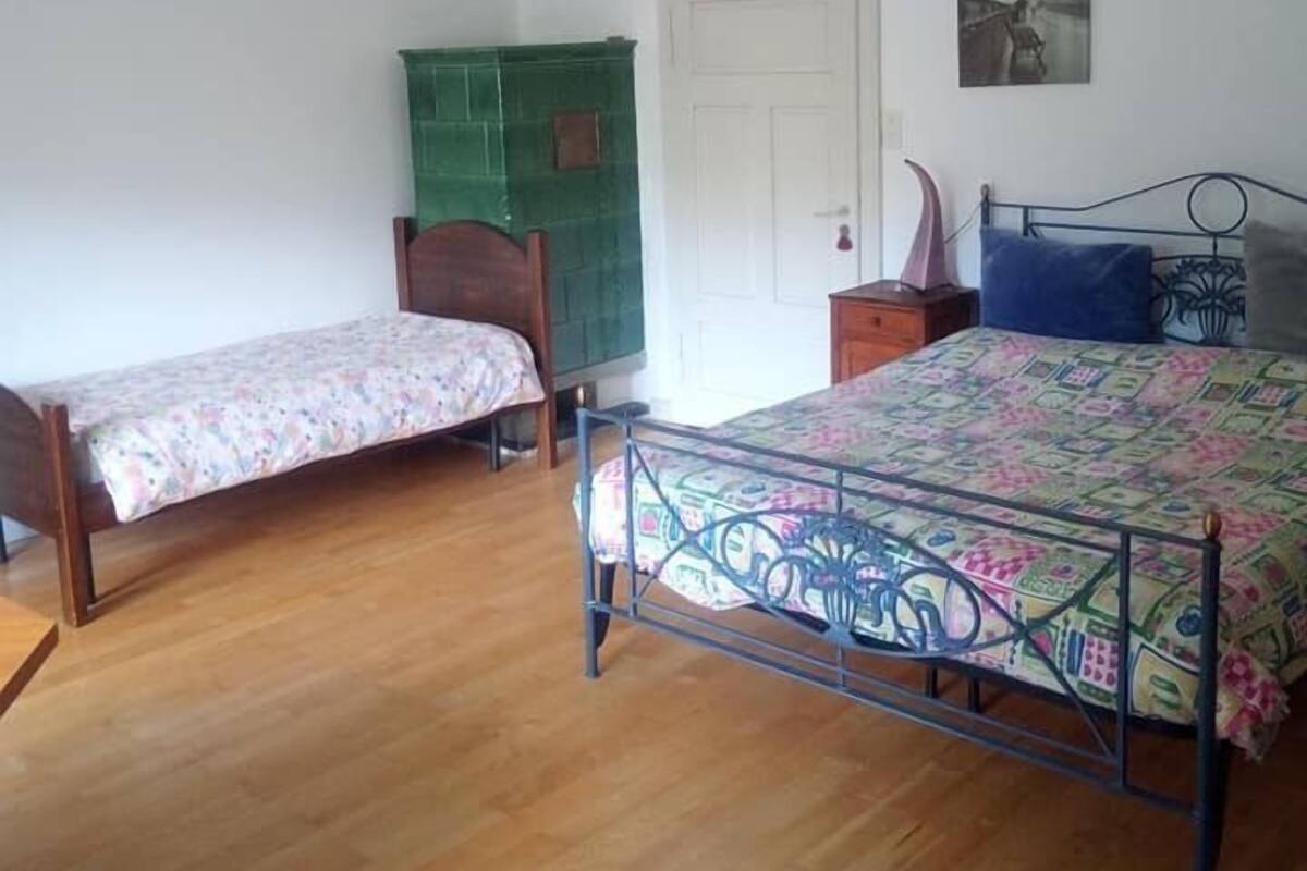 A bedroom with two single beds, a green cabinet, a white door, and a wall-mounted picture.