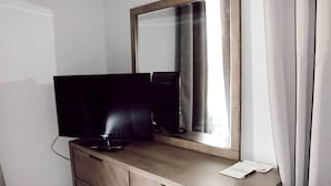 Et hotelværelse med en trækommode, et fladskærms-tv og et spejl.