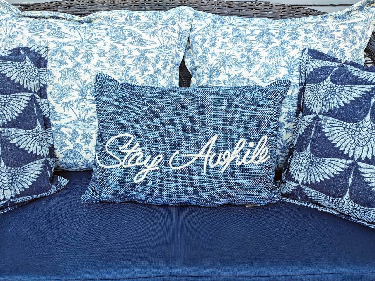 Un canapé bleu agrémenté de coussins à motifs et d’un coussin central sur lequel est inscrit le texte « Restez éveillé ».
