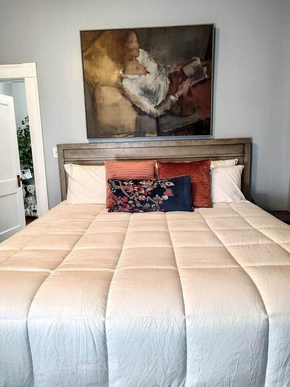 Une chambre à coucher avec un grand lit, une tête de lit en bois et un tableau au-dessus du lit.