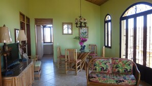 A spacious living room with a high ceiling, a dining area with chairs and a table, and a large window with a view. - Safe double gated properity with amazing views (Garza)