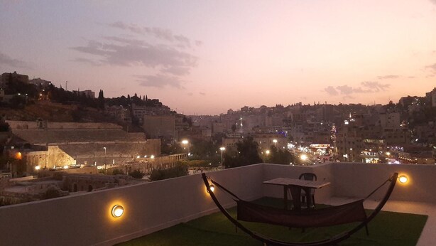 Une terrasse sur le toit, avec un hamac, une table et des chaises, d’où l’on peut admirer la vue sur la ville au crépuscule.