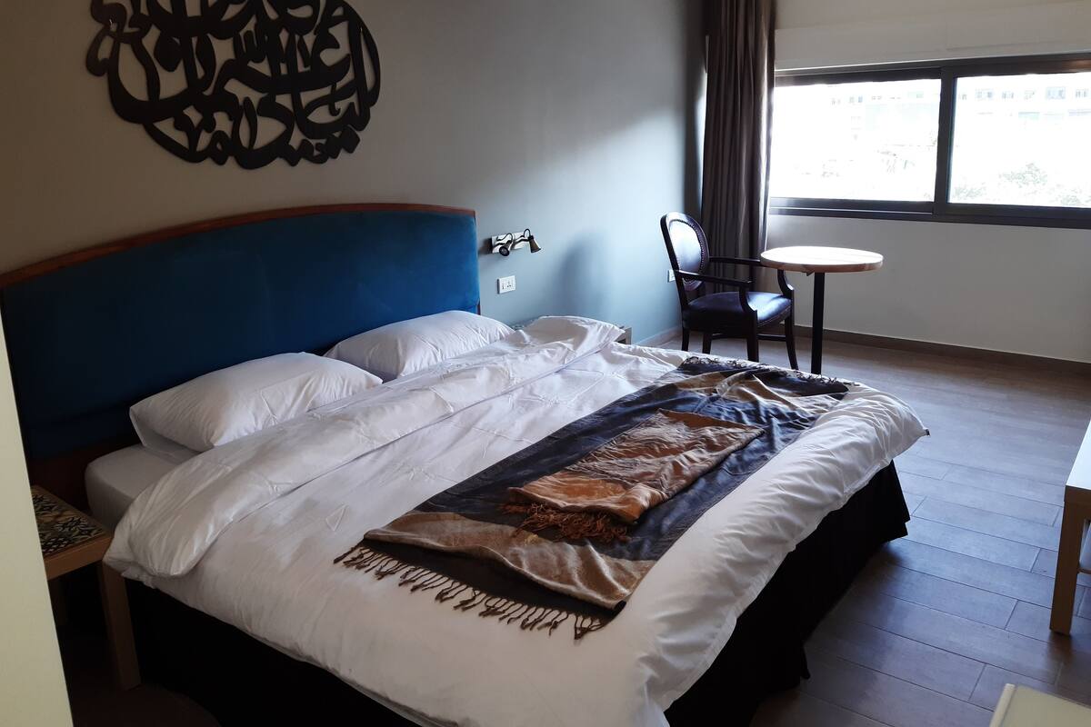A hotel room with a large bed, a desk, and a chair.