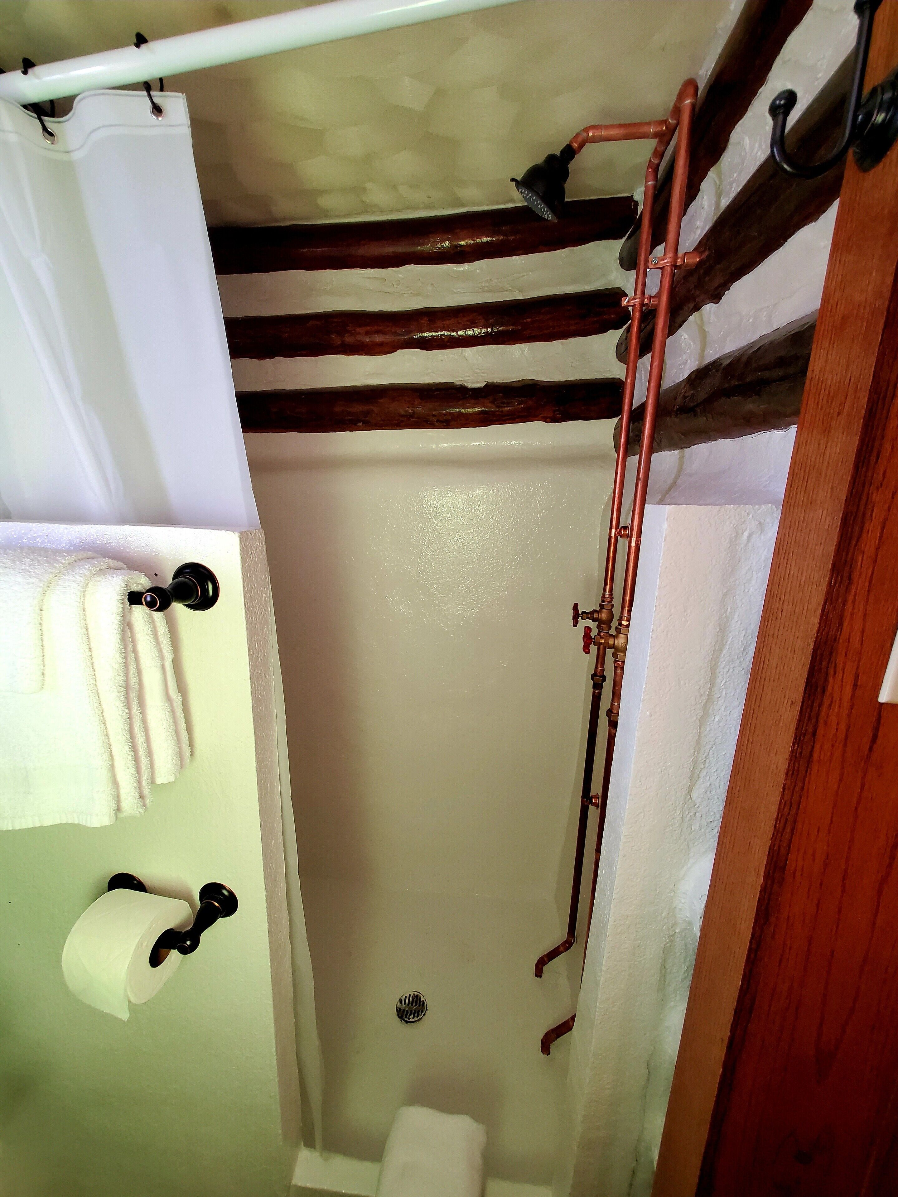 Un baño con ducha, inodoro y perchero para toallas.