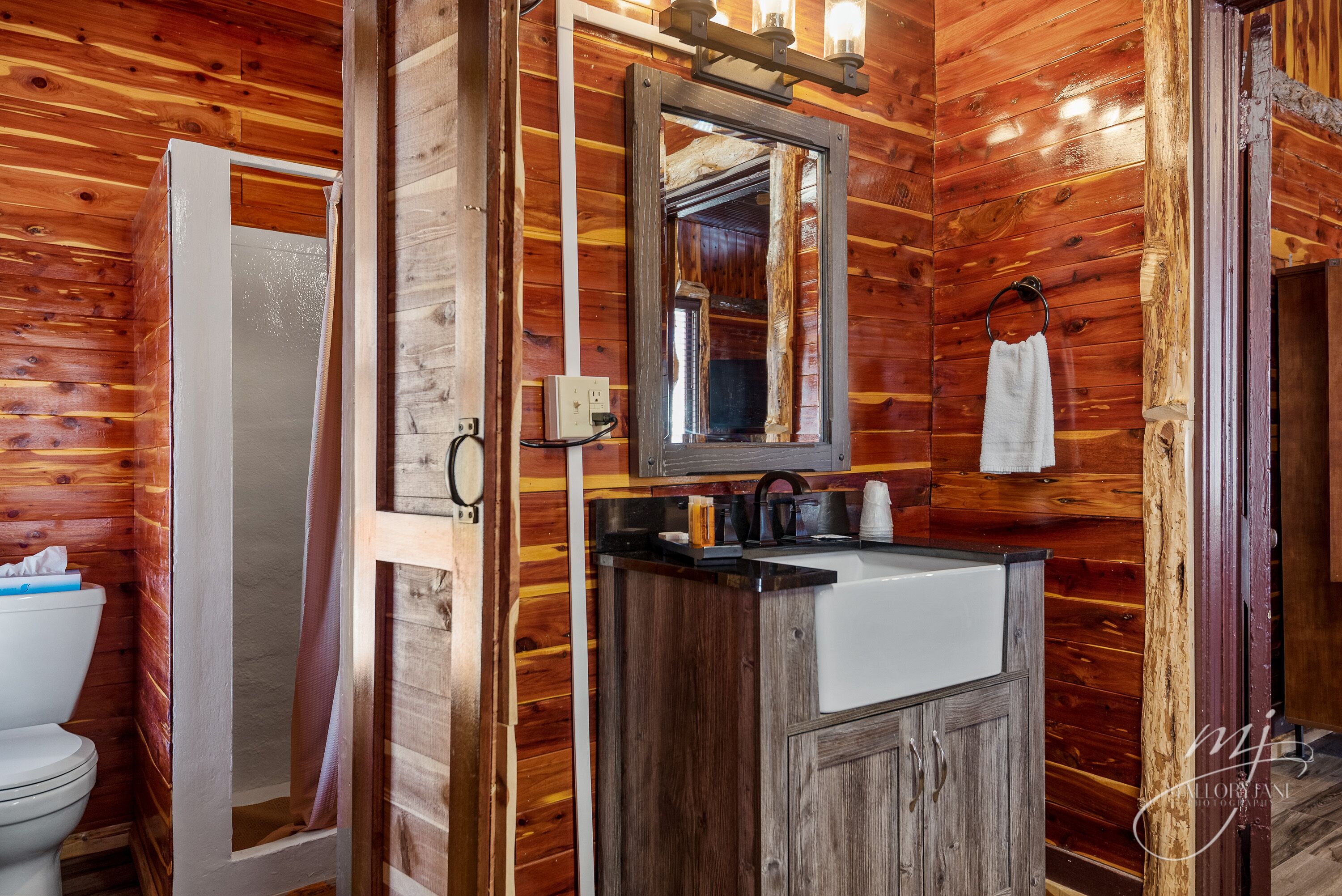 A wooden cabin bathroom with a wooden vanity, a mirror, and a shower.