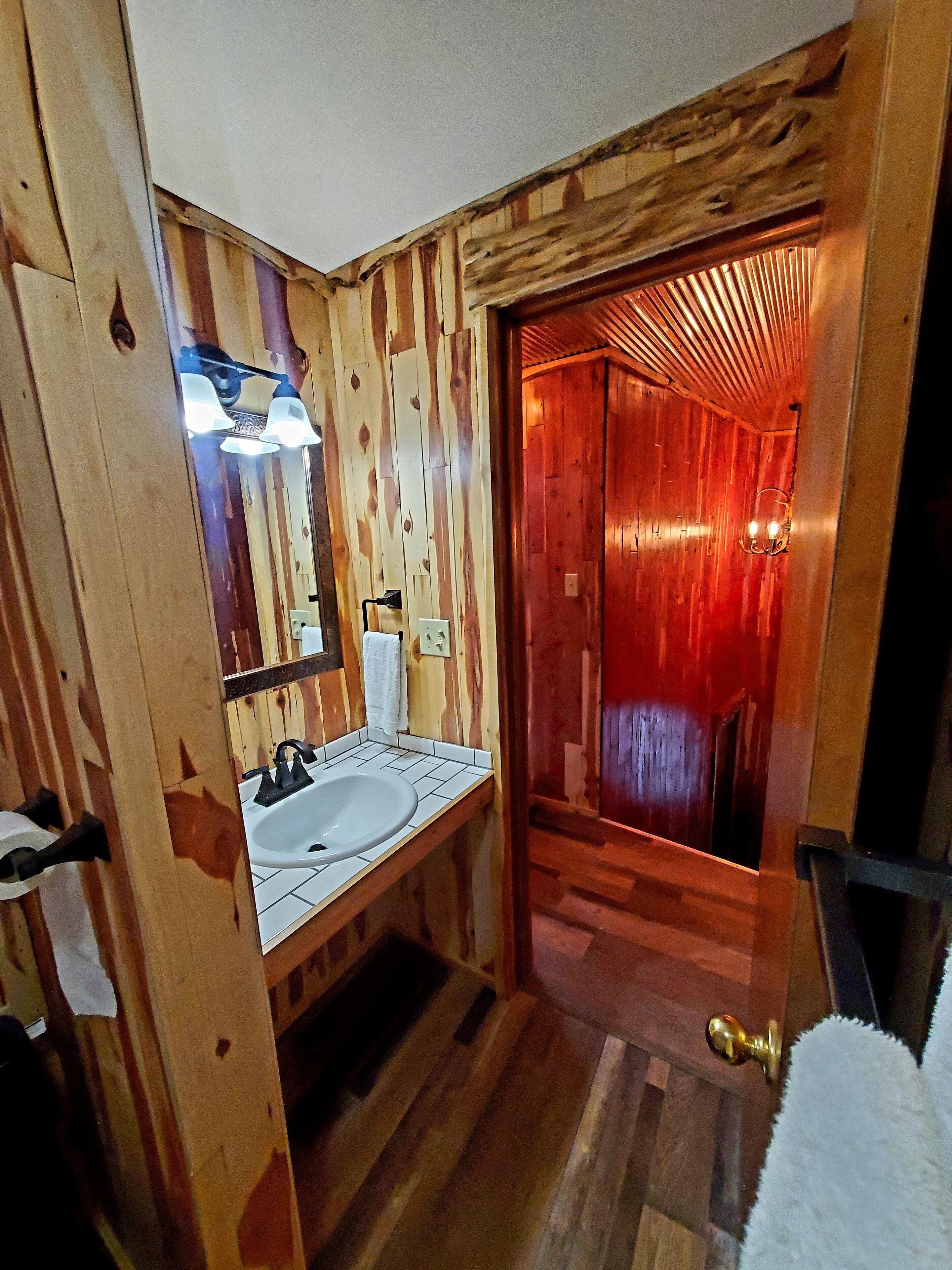 A wooden bathroom with a sink, mirror, and towel rack.