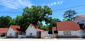A row of log cabins with red roofs, white walls, and a white picket fence in front.