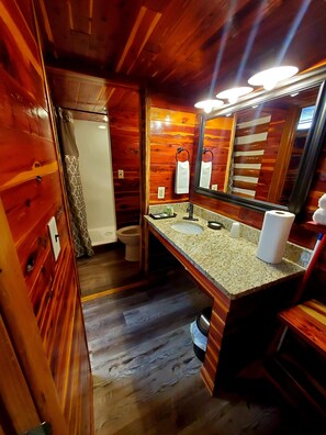 A wooden cabin bathroom with a sink, mirror, and toilet.
