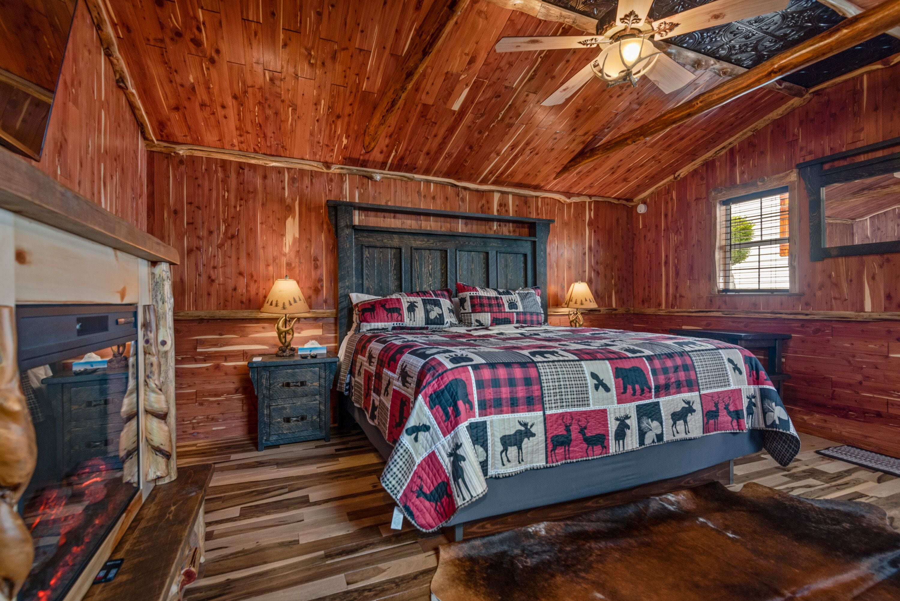 Ein rustikales Schlafzimmer aus Holz mit einem Bett, zwei Nachttischen, einem Deckenventilator und einem Fenster.