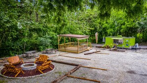 A picnic area with wooden chairs, a fire pit, and a covered seating area. - Log Cabin Inn (Eureka Springs)