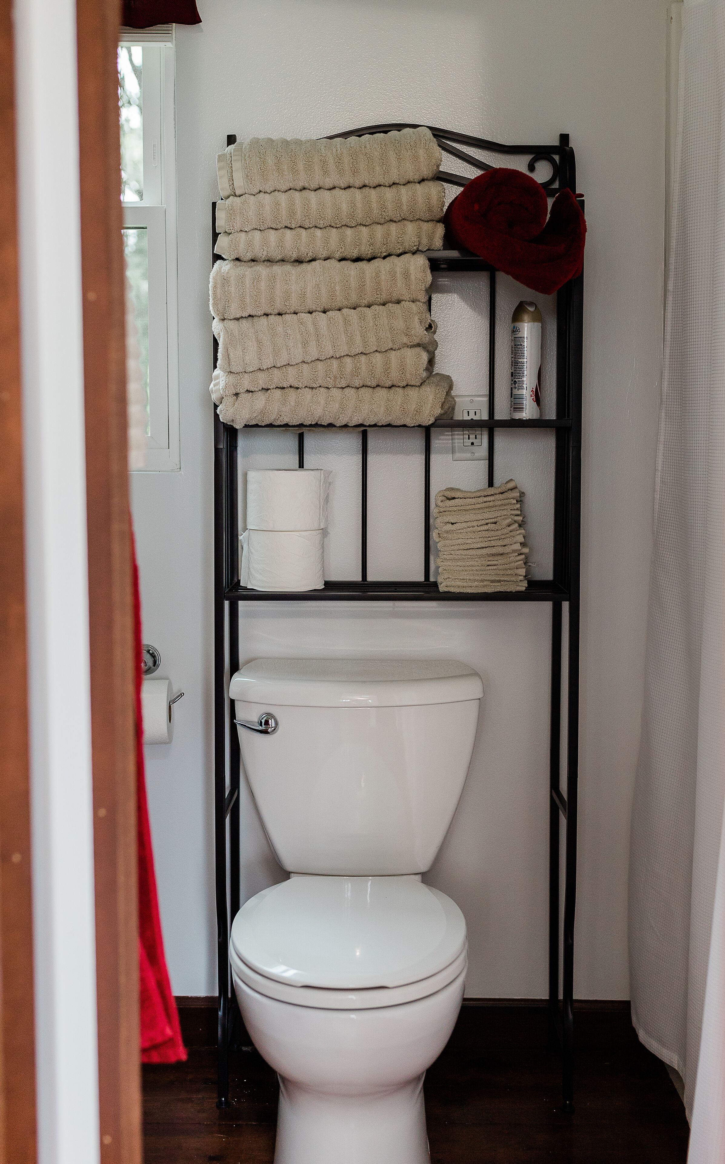 Un baño con inodoro, un perchero con toallas dobladas y una botella de jabón para manos.