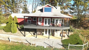 A two-story house with a balcony, stone foundation, and a red exterior.