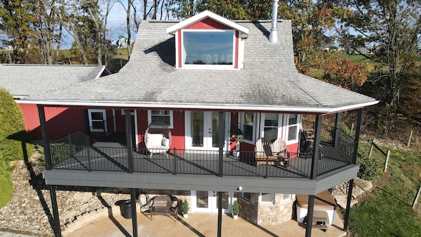 A two-story house with a covered porch, a chimney, and a large window.