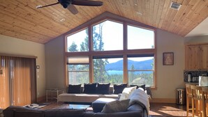 Una sala de estar acogedora con un amplio ventanal que ofrece una vista panorámica de la montaña, un ventilador de techo y un techo de madera.
