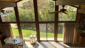 A spacious room with large windows, a ceiling fan, a dining area with a table and chairs, and a sofa with cushions. - Lake Michigan is only a short 1 minute walk away! (Macatawa)