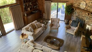 A spacious living room with a large window, a fireplace, and a bookshelf filled with books and decorative items. - Lake Michigan is only a short 1 minute walk away! (Macatawa)