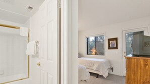 Une chambre à coucher avec un lit, une fenêtre, un téléviseur et une porte.