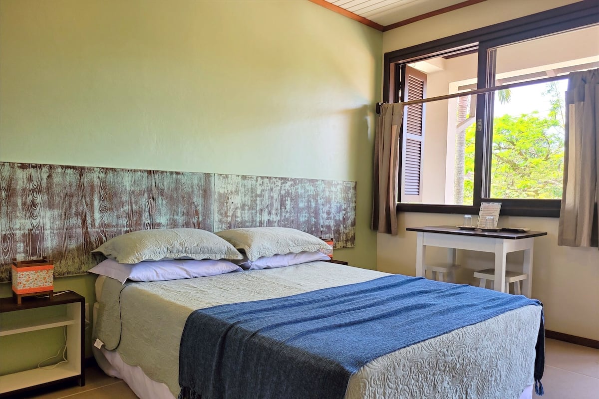 A bedroom with a bed, bedside table, and a desk with a chair.