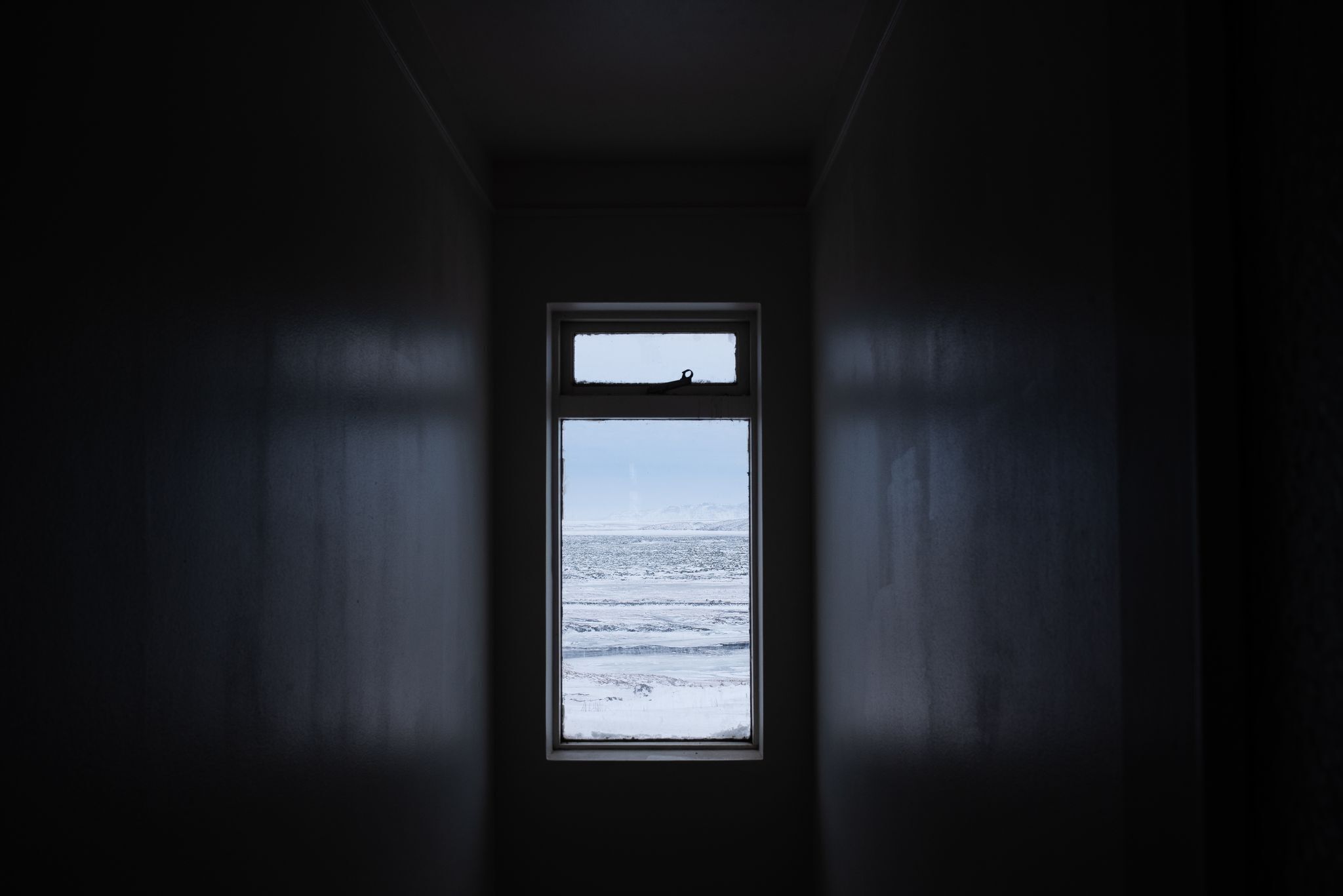 A narrow, dark hallway with a window at the end.