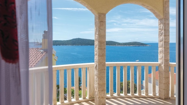 Un balcon avec vue sur la mer et une île lointaine.