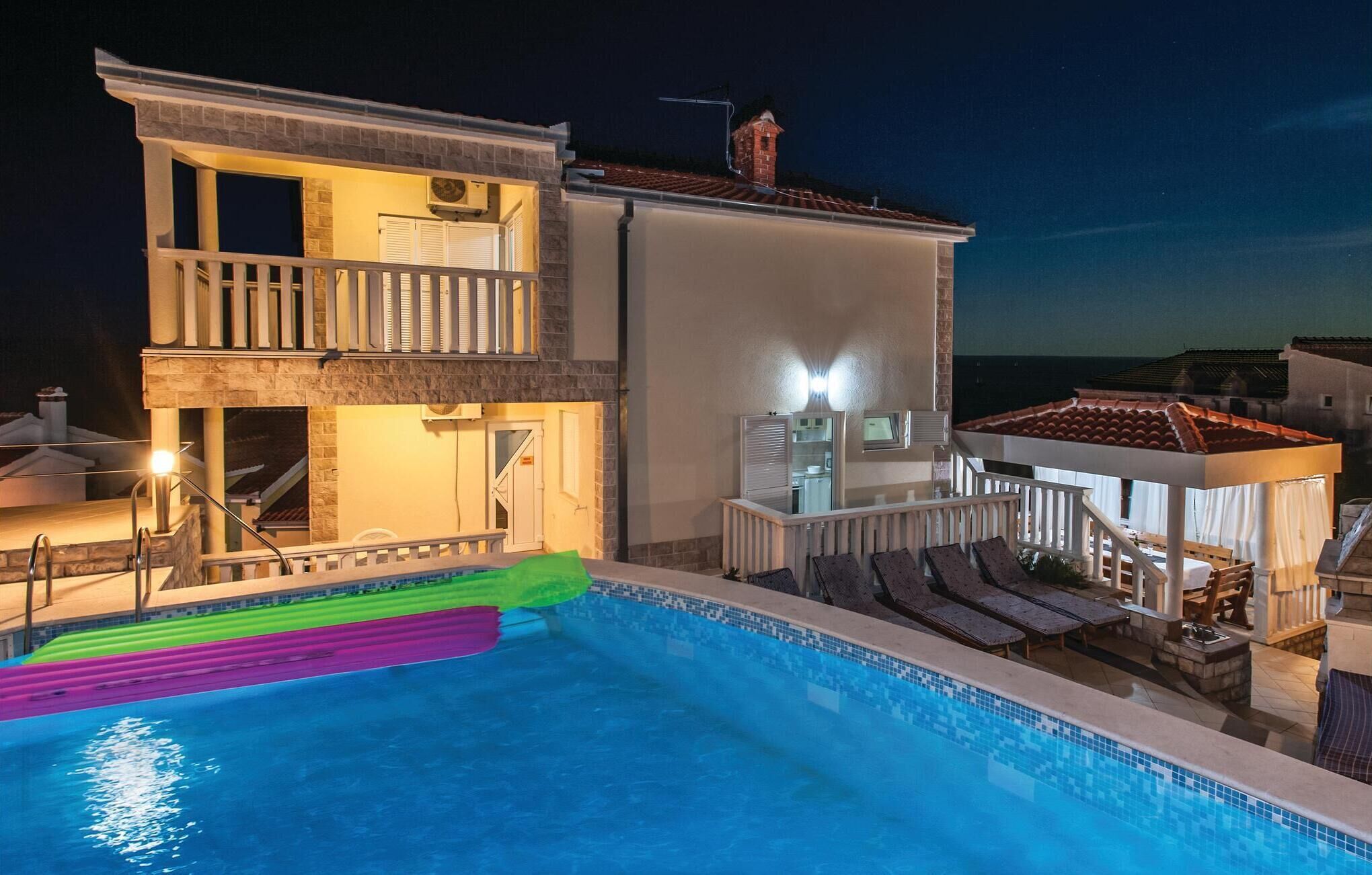 Ein zweistöckiges Haus mit Schwimmbad, einem Balkon und einem kleinen Anbau mit Dach.