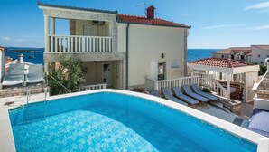 Un bâtiment à deux étages doté d’une piscine, d’un espace extérieur aménagé et offrant une vue sur la mer.
