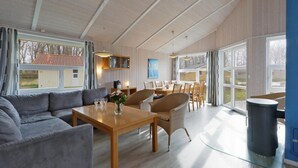 Amplia sala de estar con sofá, mesa de comedor y sillas. Una ventana grande ofrece vistas al exterior.
