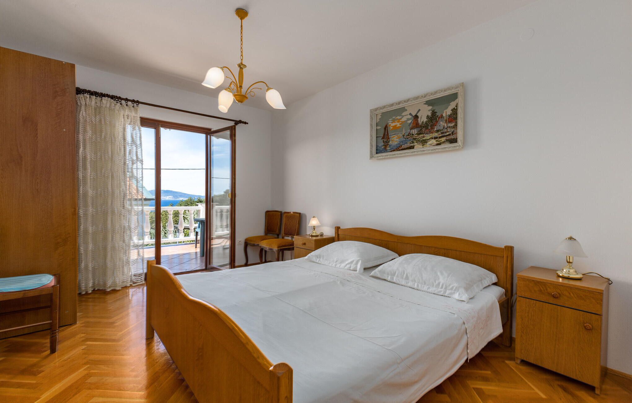 Et soveværelse med en træseng, et natbord, en stol og en balkon med udsigt til bjergene.