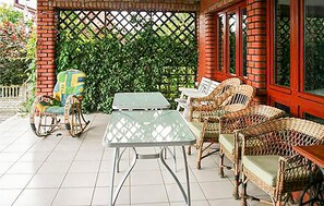 A covered patio area with wicker furniture, a table, and chairs.