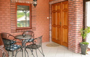A brick exterior with a wooden door, a window, and a small table with chairs.