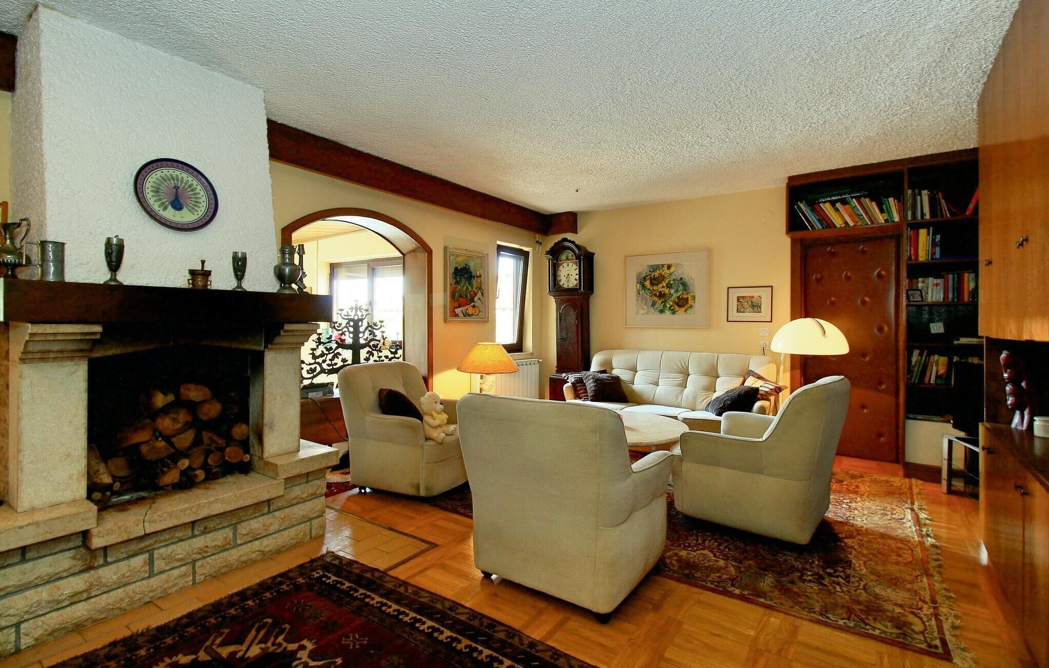 A cozy living room with a fireplace, a large clock, and a bookshelf.