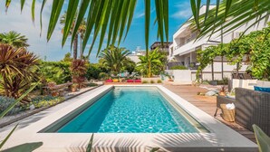A rectangular swimming pool with clear blue water, surrounded by a wooden deck and various tropical plants. - Luxurious home in Medulin with private swimming pool, can be inside or outside (Medulin)