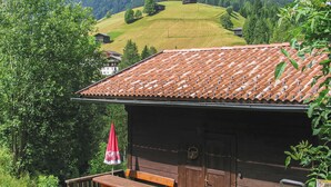 Eine Holzhütte mit einem Ziegeldach, einer Bank und einem Sonnenschirm auf dem Balkon.
