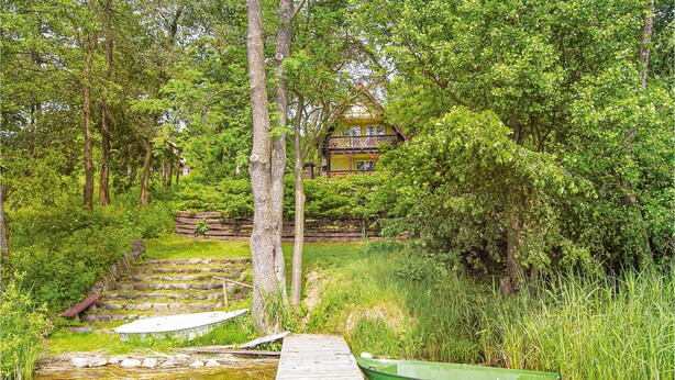 A wooden dock leading to a green boat with the license plate "WM-OLS-2232-A" in a lush, green forested area with a house in the background. - Nice home in Gietrzwald (Gietrzwald)
