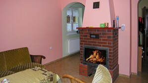 A living room with a brick fireplace, a sofa, and a table with a decorative tablecloth. - Nice home in Gietrzwald (Gietrzwald)