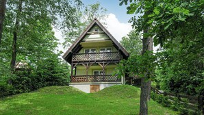 A traditional chalet with a steeply pitched roof, a balcony with lattice railing, and a wooden door. - Nice home in Gietrzwald (Gietrzwald)